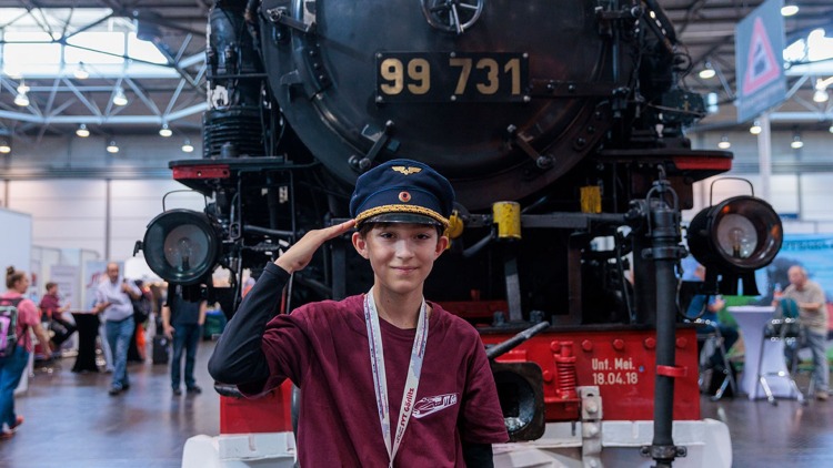 Hobbymesse Leipzig: Junge mit Eisenbahner-Mütze vor Lokomotive
