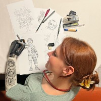 Lara Wilkin, Referentin des Weltkongresses, bringt ihre Erfahrungen aus der Armprothetik in Forschung und Praxis ein. Zur Eröffnung zeigt sie eine mit ihrer Prothesenhand im Februar 2026 erstellte Zeichnung, die ihre Perspektive auf 50 Jahre OTWorld sichtbar macht. 